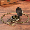 A gold-toned chain watch case with an open lid revealing seven metal polyhedral dice on a wooden surface.