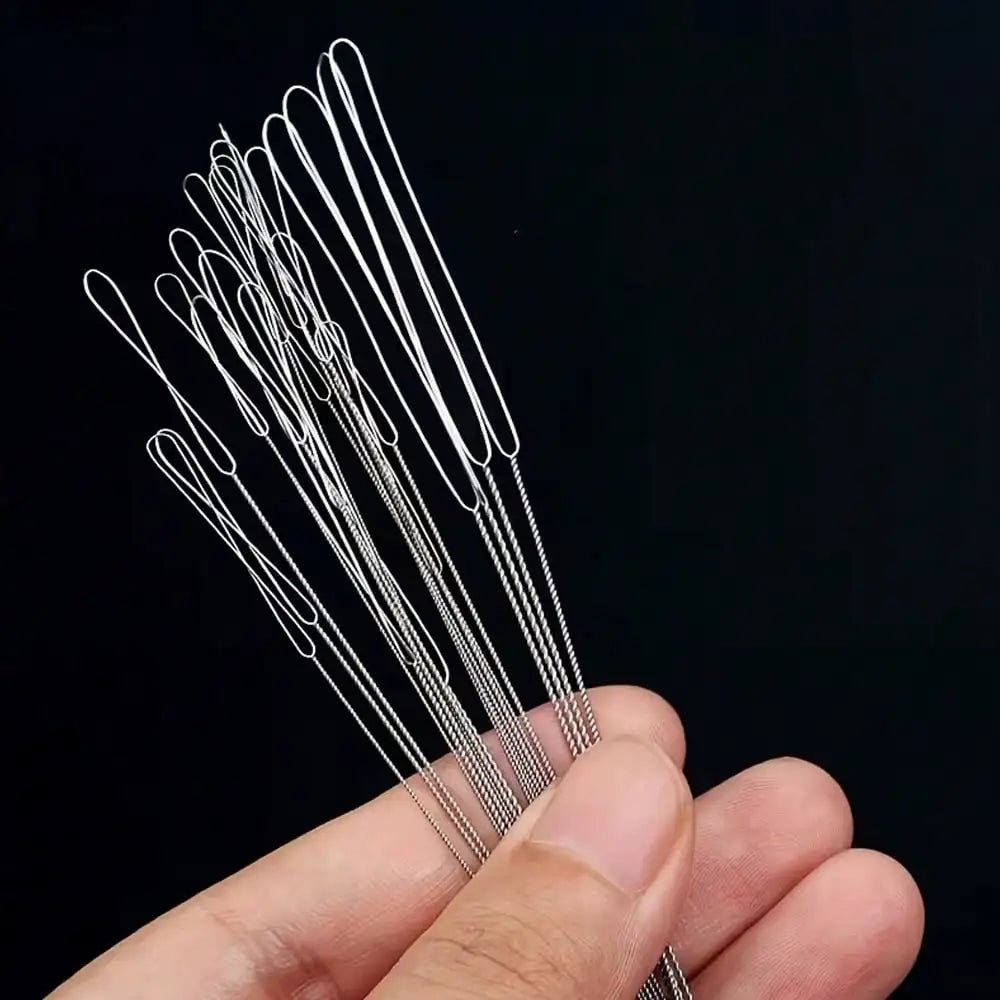 A hand holds a set of seven ultra-fine beading needles for jewelry making against a dark background.