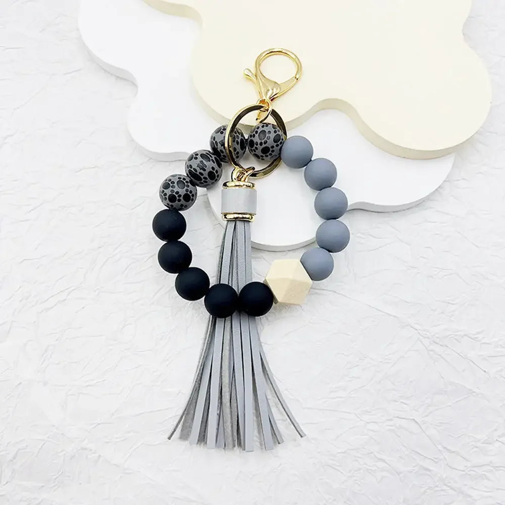 A boho silicone bead keychain featuring black and gray beads with a silver tassel.