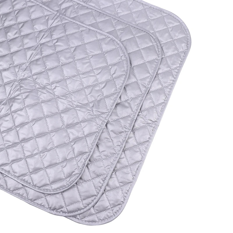 A stack of light gray quilted ironing mats for wrinkle removal.