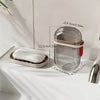 A clear plastic portable travel soap box with a drainage lid and a white soap bar resting on a tray.