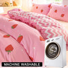 Pink strawberry print duvet cover set and pillowcases displayed on a bed next to a white washing machine.