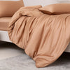 Luxuriöses beige Bambus-Duvetcover-Set über einem Bett, mit weichen Falten und glatter Stoff.