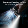 A hand holds a dual-mode flashlight illuminating a bright beam against a dark background.