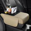 A beige car armrest cushion with storage and cup holders is shown in a black car interior.