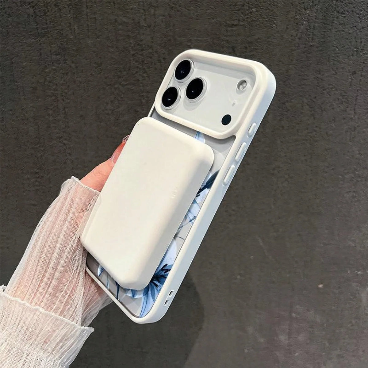 A white magnetic phone case with a matte clear finish and a blue lily design is held in a hand against a dark background.