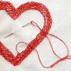 A set of red self-threading sewing needles with a side hole design laid out on white fabric.