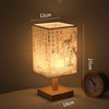 A square Chinese style table lamp with a linen shade emits warm light on a wooden surface.