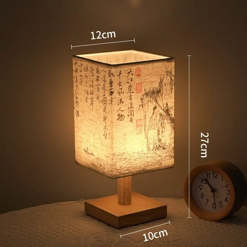 A square Chinese style table lamp with a linen shade emits warm light on a wooden surface.