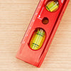 A red magnetic aluminum level ruler with V-grooves for precise angle measurement is shown on a wooden surface.