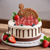 Runder Kuchen mit Erdbeeren, Blaubeeren und Holzfigur auf weißem Teller.
