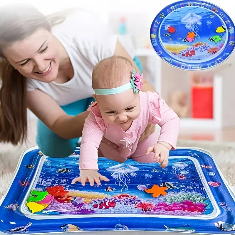 A baby is playing on a blue inflatable water play mat with colorful fish and sea creatures.
