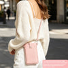 A woman wearing a cream knit sweater and white pants holds a pink PU leather crossbody bag.