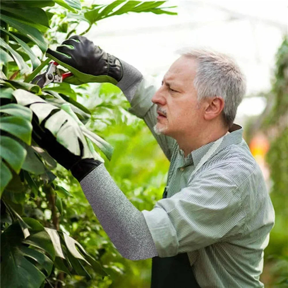 A man wearing protective gloves is inspecting a plant with cut-resistant arm sleeves.
