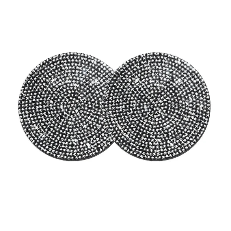A set of two round, silver-toned diamond-encrusted non-slip coasters.