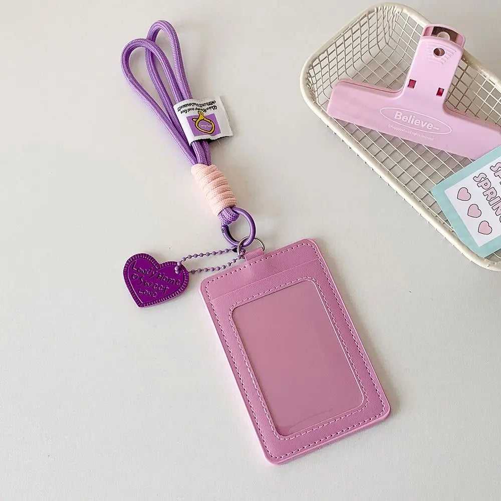 Pinkes Kunstleder-Kartenetui mit lila Lanyard und einem Netzkorb im Hintergrund