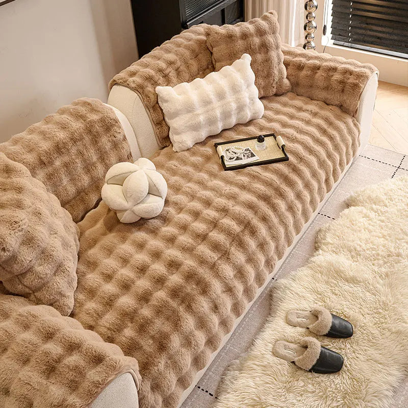 A beige plush sofa cushion cover featuring tufted texture and decorative pillows on a light-colored sofa.