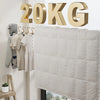 A beige quilted blanket hangs next to a gold text sign reading 20KG, with clothes on a wooden hanger nearby.