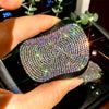 A hand holds a black, textured cup holder coaster covered in sparkling rhinestones.