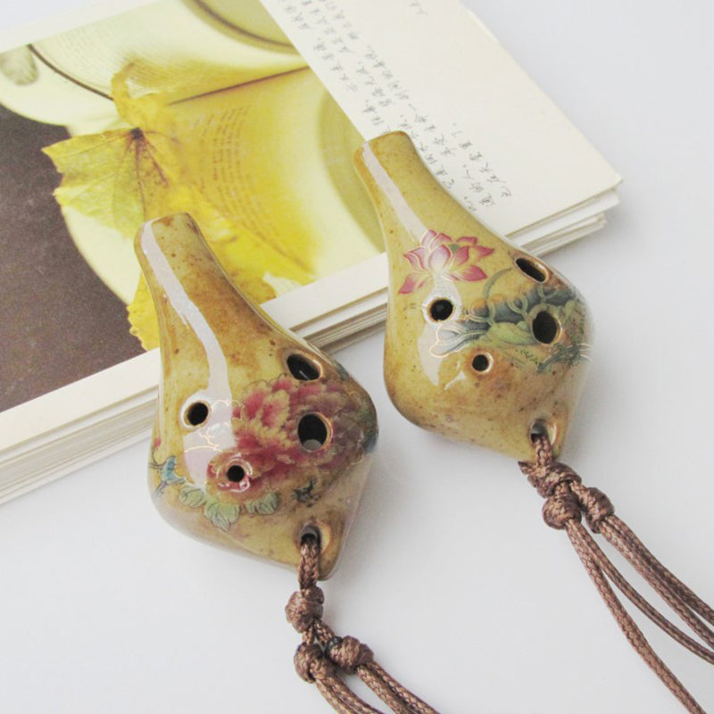 Handcrafted ceramic pendant ocarina with six holes featuring a mottled green and pink glaze.