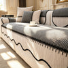 A striped chenille sofa cover with a pleated hem in gray and white fabric, displayed indoors.