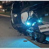 A white motorcycle is illuminated by a bright blue strobe light on the road at night.