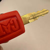A close-up view of a bright orange ignition key set for Caterpillar excavators, showing the key and plastic housing.