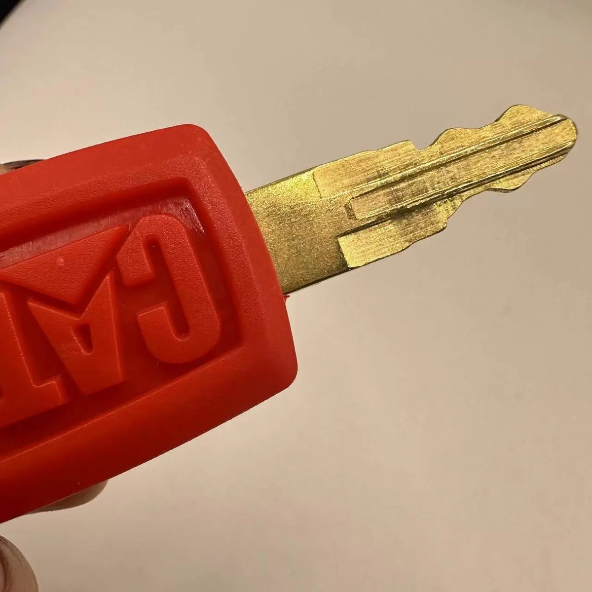 A close-up view of a bright orange ignition key set for Caterpillar excavators, showing the key and plastic housing.