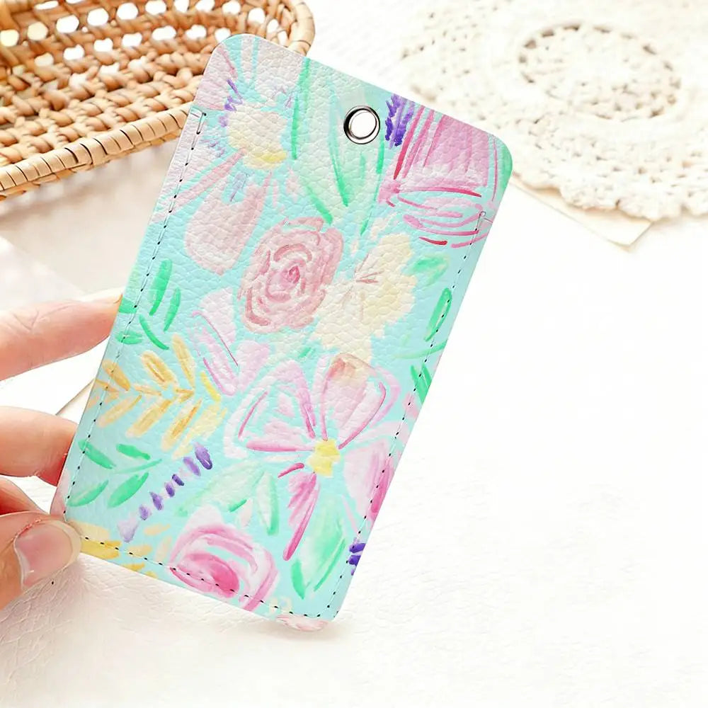 A pink and green floral patterned PU leather card holder keychain is held by a hand on a white surface.