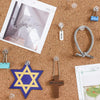 A collection of transparent push pins, including clear thumb tacks and a star-shaped pin, are scattered on brown cork board.
