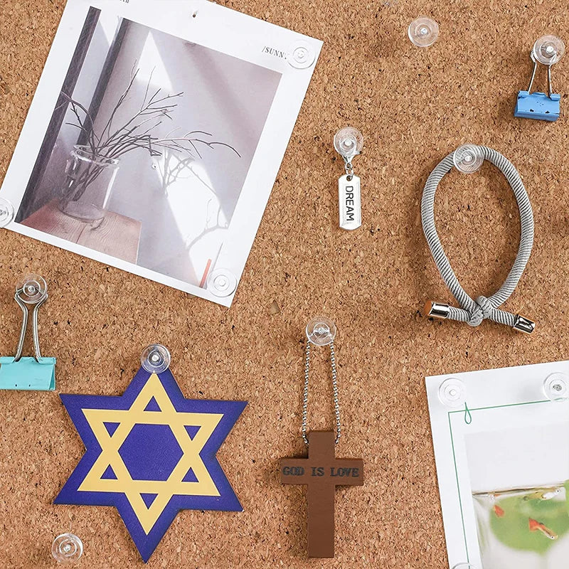 A collection of transparent push pins, including clear thumb tacks and a star-shaped pin, are scattered on brown cork board.