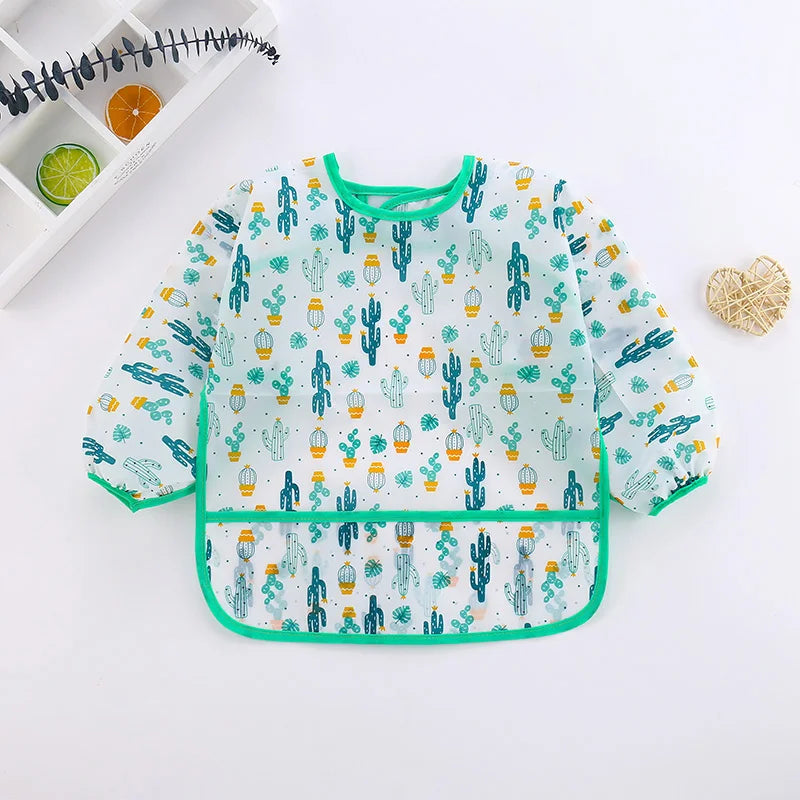 A light blue and green patterned kids waterproof long sleeve smock and feeding bib