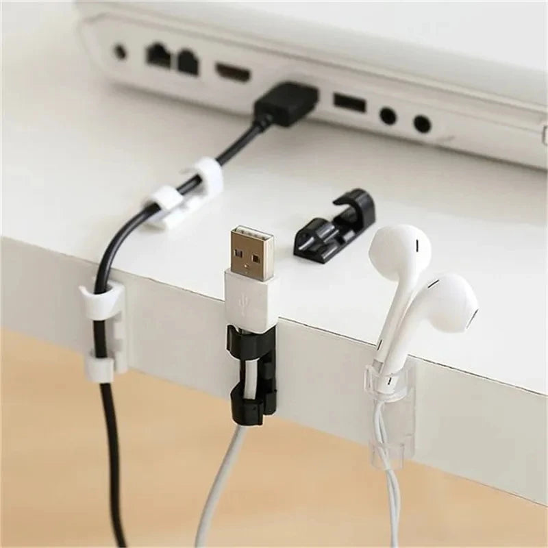 Desktop cable management clips holding a USB cable and white earphones on a white desk surface