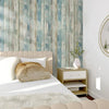 A bedroom featuring a headboard, white bedding, and a vintage wood grain peel and stick wallpaper in blue and gray tones.