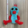 A plush toy of an Opila bird with blue body and red accents, hanging from a silver loop against a measuring tape.