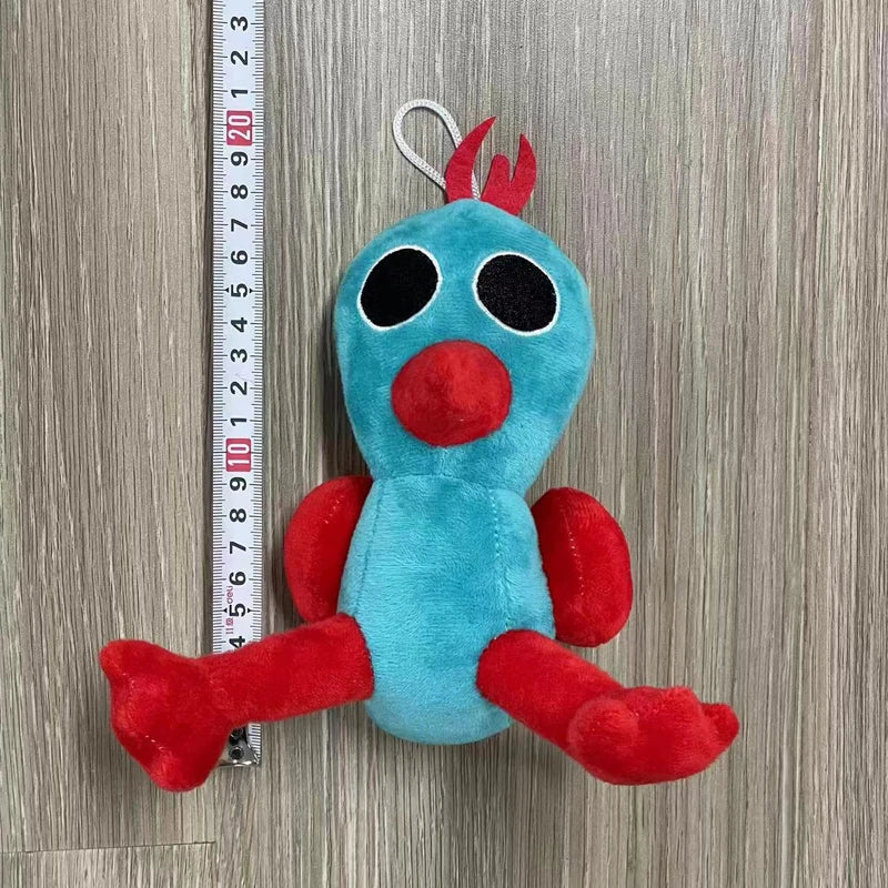 A plush toy of an Opila bird with blue body and red accents, hanging from a silver loop against a measuring tape.