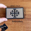 A black embroidered tactical patch featuring a Templar cross design on a light gray background.