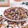 A pile of mixed natural crystal gravel stones and gemstone chips in various colors and shapes.