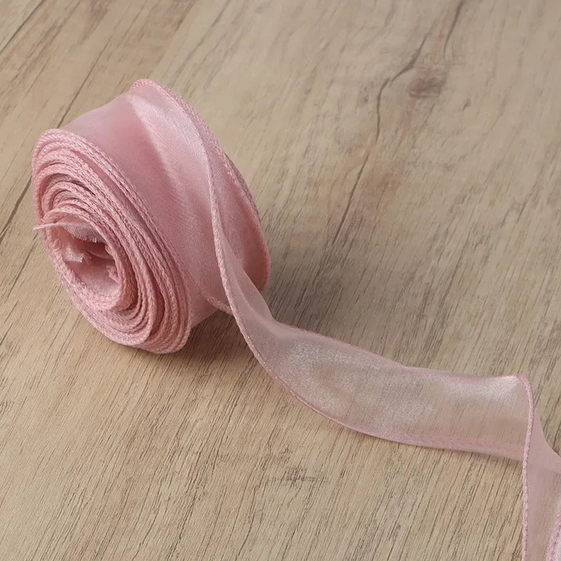 Pink organza ribbon rolled into a coil and unwound, showing its sheer texture.