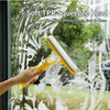 A hand uses a soft TPR squeegee head to clean water streaks off a window.