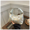Helles blaues Seid크rossbody-Tasche mit goldener Perlenstickerei auf Holzoberfläche.