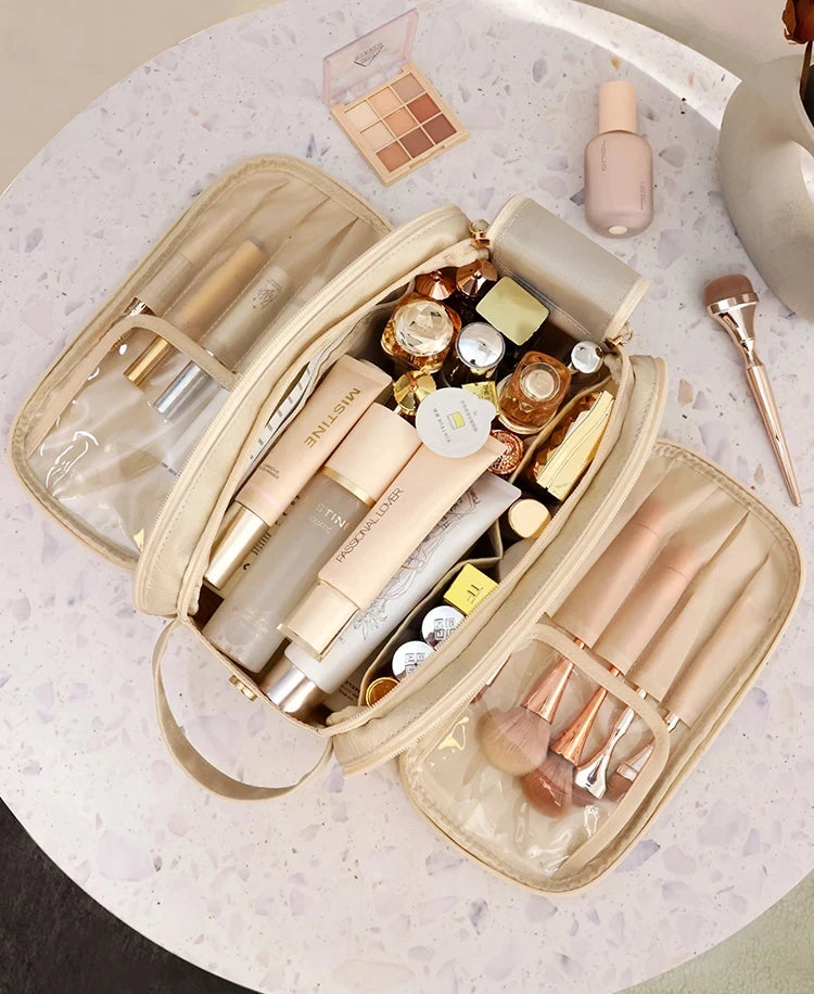 A beige cosmetic bag filled with various makeup products including lipsticks and a powder compact on a light surface.