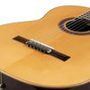 A close-up of a classical guitar showing a silver-plated nylon string set being tuned on the fretboard.