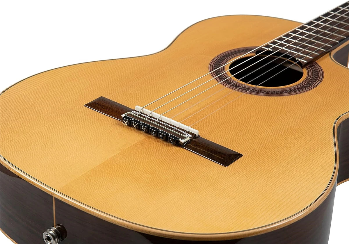 A close-up of a classical guitar showing a silver-plated nylon string set being tuned on the fretboard.