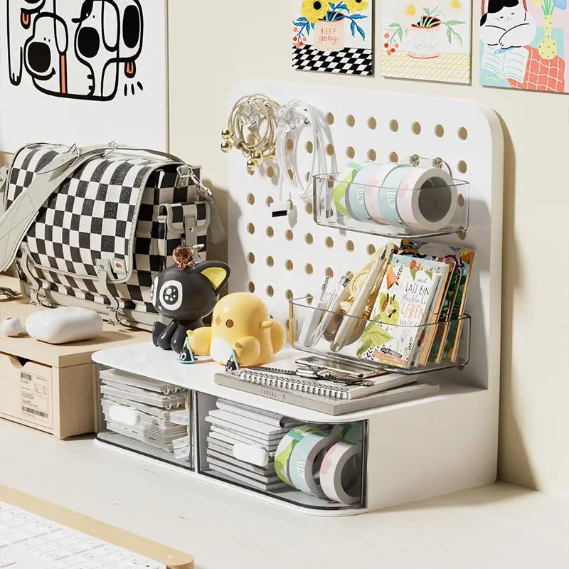 A white desk organizer featuring a grid of transparent drawers and decorative elements like a stuffed animal and various stat
