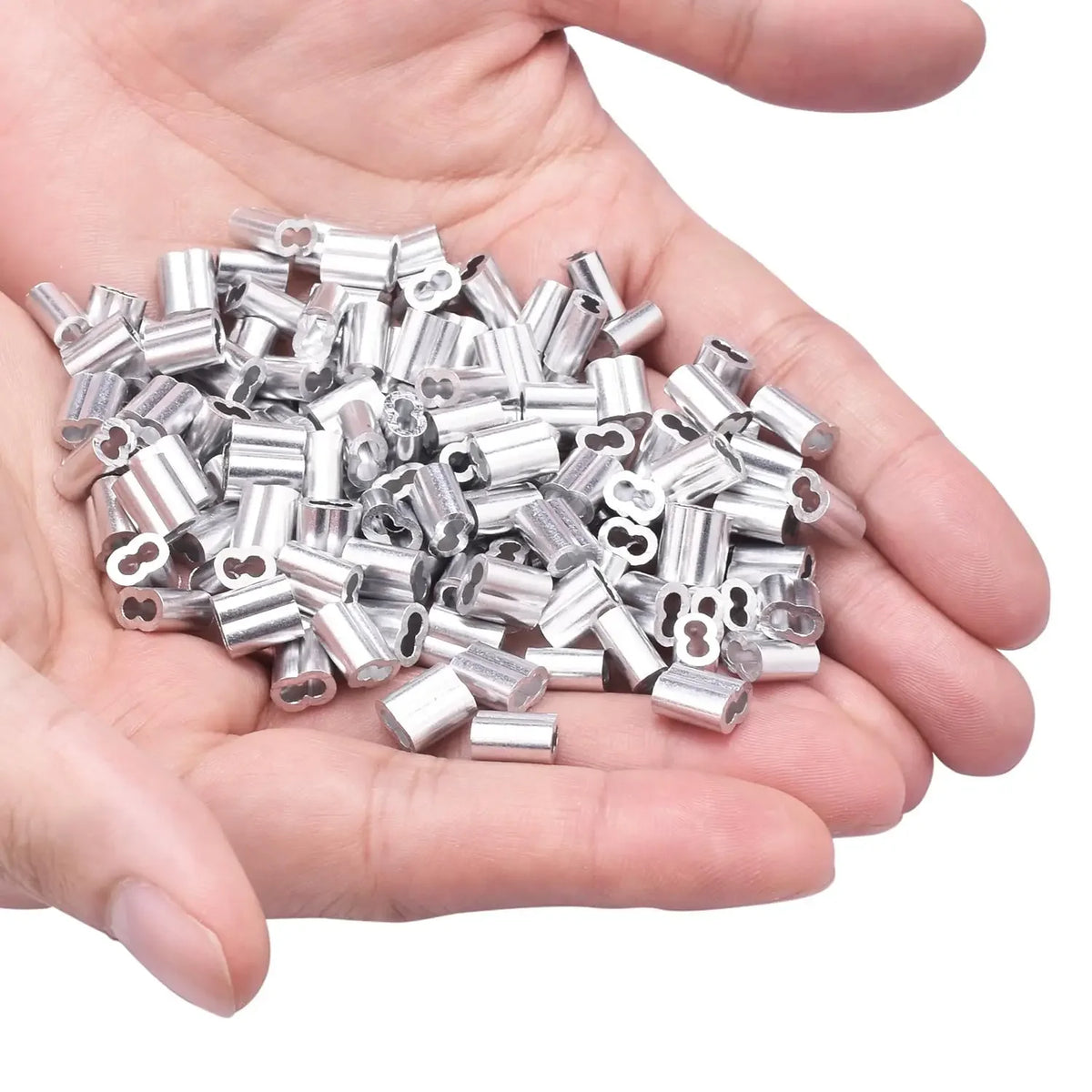 A hand holds a pile of silver aluminum double barrel crimp sleeves for wire rope.