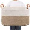 A beige woven cotton rope storage basket with a natural fiber accent band is held by a person.