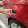 A hand is operating a car dent puller kit with a handle lift and power remover on the red body panel of a car.