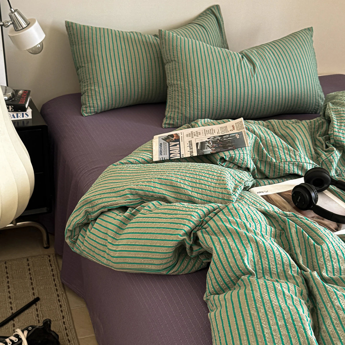A green and gold striped duvet cover set with matching pillowcases on a purple bed.