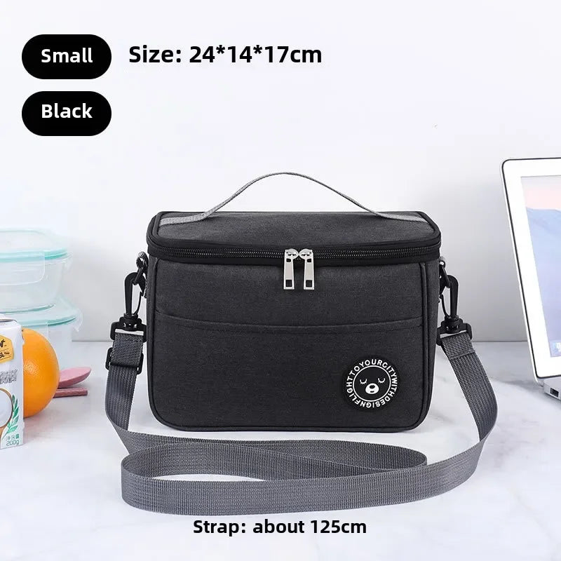 Black insulated lunch bag with a gray shoulder strap shown on a white surface.